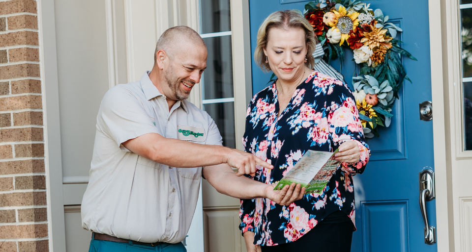 Grass Master discussing lawn care services and program with customer at their home.